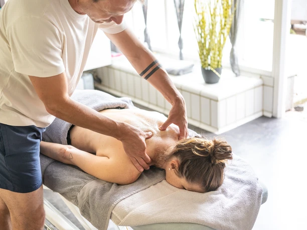 Masseur löst mit beiden Händen Verspannungen im Rücken einer Frau in der Driburg Therme.