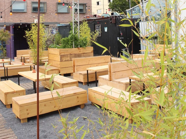 Der schwarze Hase Holzbänke auf einem modernen Außenbereich mit urbanem Ambiente und umgebenden Pflanzen.