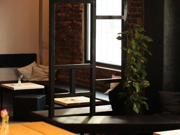 Der schwarze Hase Ein stilvolles Interieur mit Ziegelwänden, einer Sprossenfensterfront und einem Efeu.