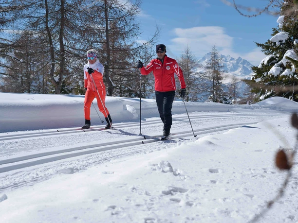 Cross-country skiing course on the groomed trail of the Riederalp Cross-country skiing taster course Riederalp with two participants on a groomed trail against a snowy Alpine backdrop