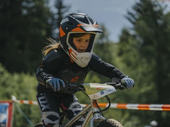 Junge Bikerin im Kinderbikekurs Bettmeralp Kinderbikekurs Bettmeralp mit Nahaufnahme einer jungen Bikerin in voller Schutzausrüstung beim FahrenChildren's bike course Bettmeralp with close-up of a young biker in full protective gear ridingCours de VTT pour enfants à Bettmeralp avec gros plan sur une jeune vététiste en train de rouler avec son équipement de protection complet