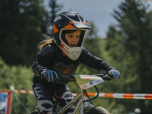 Young biker on the Bettmeralp children's bike course Children's bike course Bettmeralp with close-up of a young biker in full protective gear riding