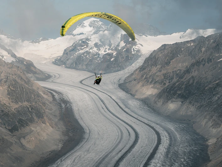 Paragliding am Aletschgletscher Aletsch Fly Deluxe Gleitschirmflug über den Grossen Aletschgletscher mit Pilot und Passagier vor eindrucksvoller GletscherkulisseAletsch Fly Deluxe paragliding flight over the Great Aletsch Glacier with pilot and passenger against an impressive glacier backdropAletsch Fly Deluxe Vol en parapente au-dessus du grand glacier d'Aletsch avec pilote et passager devant un impressionnant décor de glacier