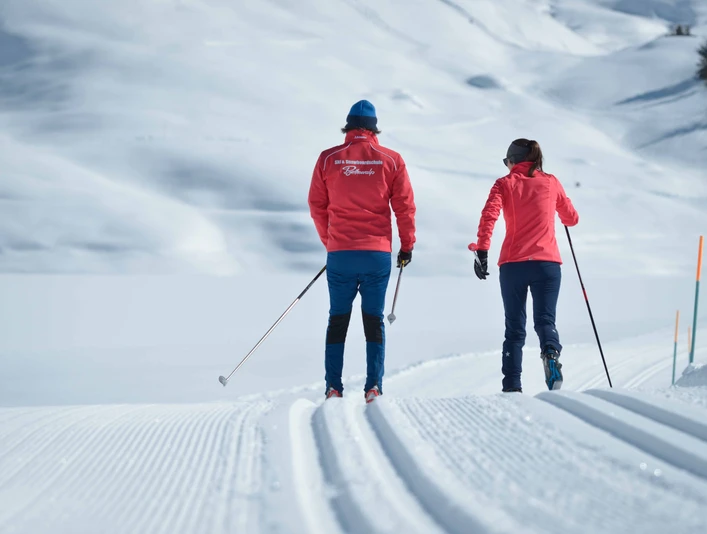 Out and about together on the trail Langlauf Schnupperkurs Bettmeralp in der Aletsch Arena mit zwei Teilnehmern nebeneinander auf verschneiter WinterloipeBettmeralp cross-country skiing taster course in the Aletsch Arena with two participants side by side on a snow-covered winter trailCours d'initiation au ski de fond à Bettmeralp dans l'Aletsch Arena avec deux participants côte à côte sur une piste d'hiver enneigée