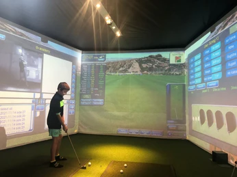 Indoor golf training for children Indoor Golf Bettmeralp im Sportzentrum Bachtla mit Kind am Golfsimulator beim Training auf virtueller Driving RangeIndoor Golf Bettmeralp at the Bachtla sports center with a child on the golf simulator while training on the virtual driving rangeIndoor Golf Bettmeralp au centre sportif Bachtla avec un enfant sur le simulateur de golf lors de l'entraînement sur le driving range virtuel