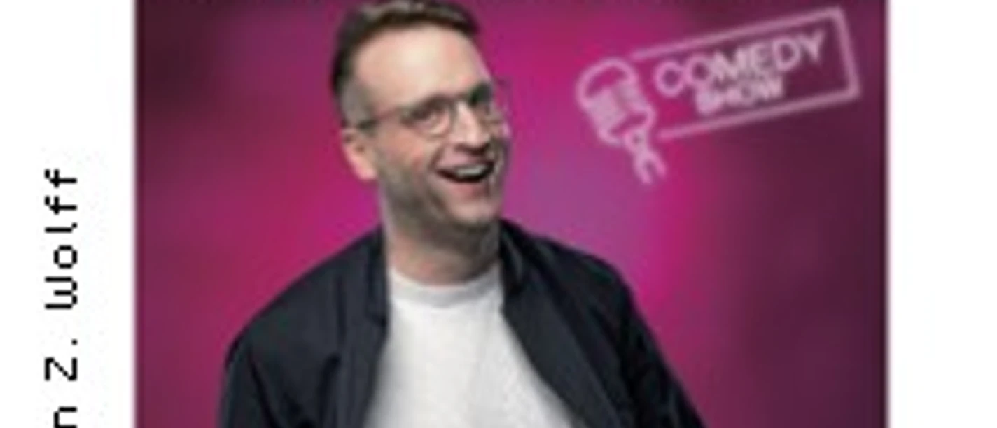 Lächelnde Person vor Comedy-Poster mit neonfarbenem Titelmotiv