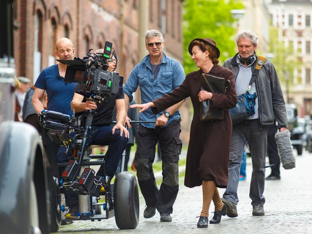 Filmdreh_Jeder Stirbt Für Sich Allein_emma-thompson-20150506-15281_NikolaiSchmidt.jpg Emma Thompson lacht mit Team während Filmszene-Dreh in einer städtischen Altstadtumgebung.
