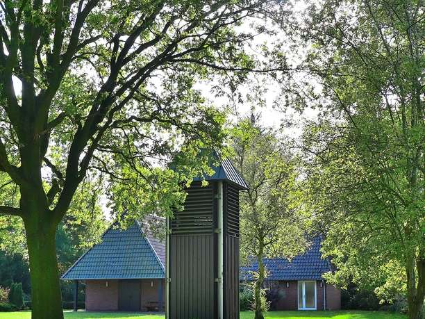 Kapelle Godensholt Kleine Kapelle mit dunklem Holzturm, umgeben von grüner Landschaft unter blauem Himmel.