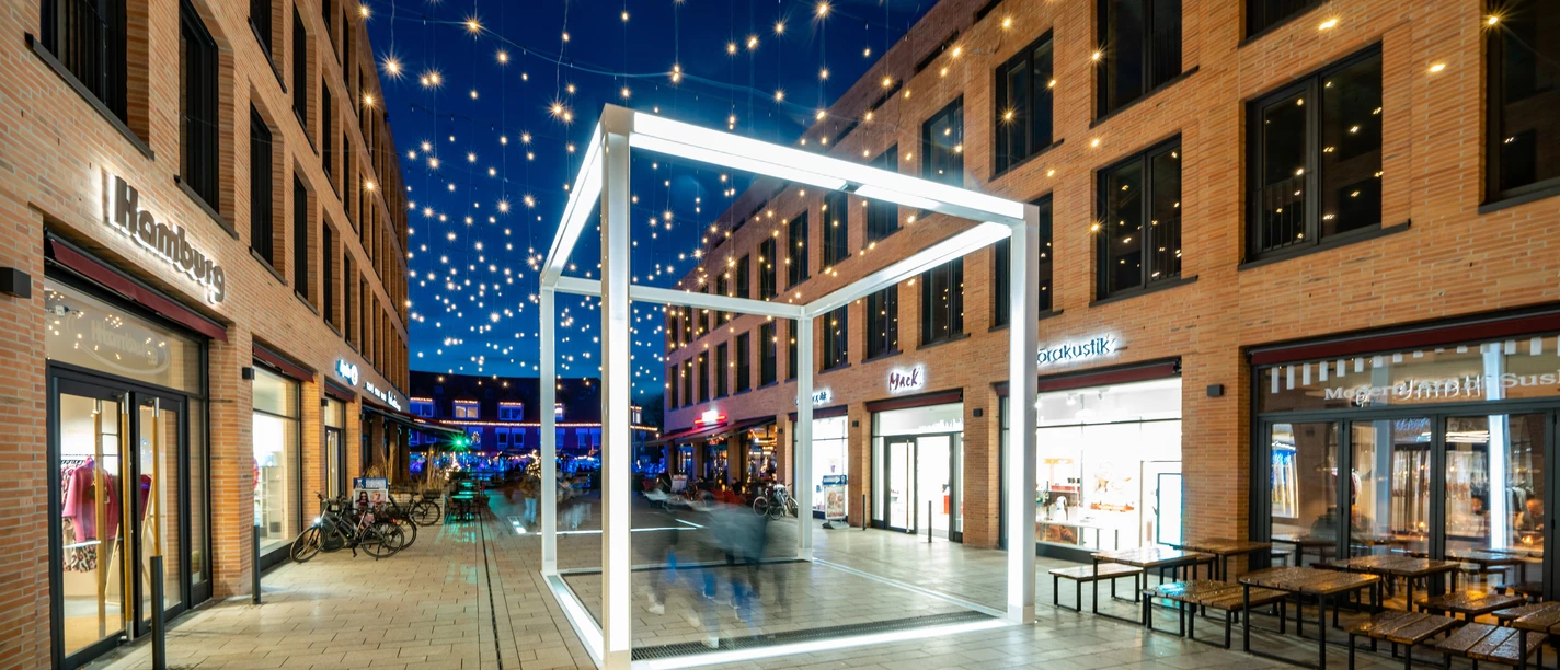Monheim Cube Leuchtender Monheim Cube in einer beleuchteten Fußgängerzone mit scheinendem Sternenhimmel.