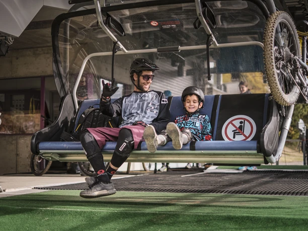 Expérience VTT dans l'Aletsch Arena Aletsch Bikepass avec des vététistes et un enfant dans le siège du télésiège Wurzenbord à Bettmeralp