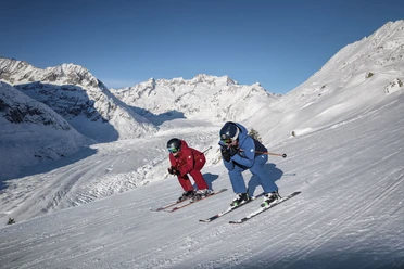Skifahren mit Blick auf den Aletschgletscher Skipass Aletsch Arena mit zwei Skifahrern auf perfekt präparierter Piste oberhalb des Aletschgletschers bei strahlendem Winterwetter