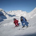 Skifahren mit Blick auf den Aletschgletscher Skipass Aletsch Arena mit zwei Skifahrern auf perfekt präparierter Piste oberhalb des Aletschgletschers bei strahlendem WinterwetterAletsch Arena ski pass with two skiers on perfectly groomed slopes above the Aletsch Glacier in glorious winter weatherForfait Aletsch Arena avec deux skieurs sur une piste parfaitement préparée au-dessus du glacier d'Aletsch par un temps hivernal radieux