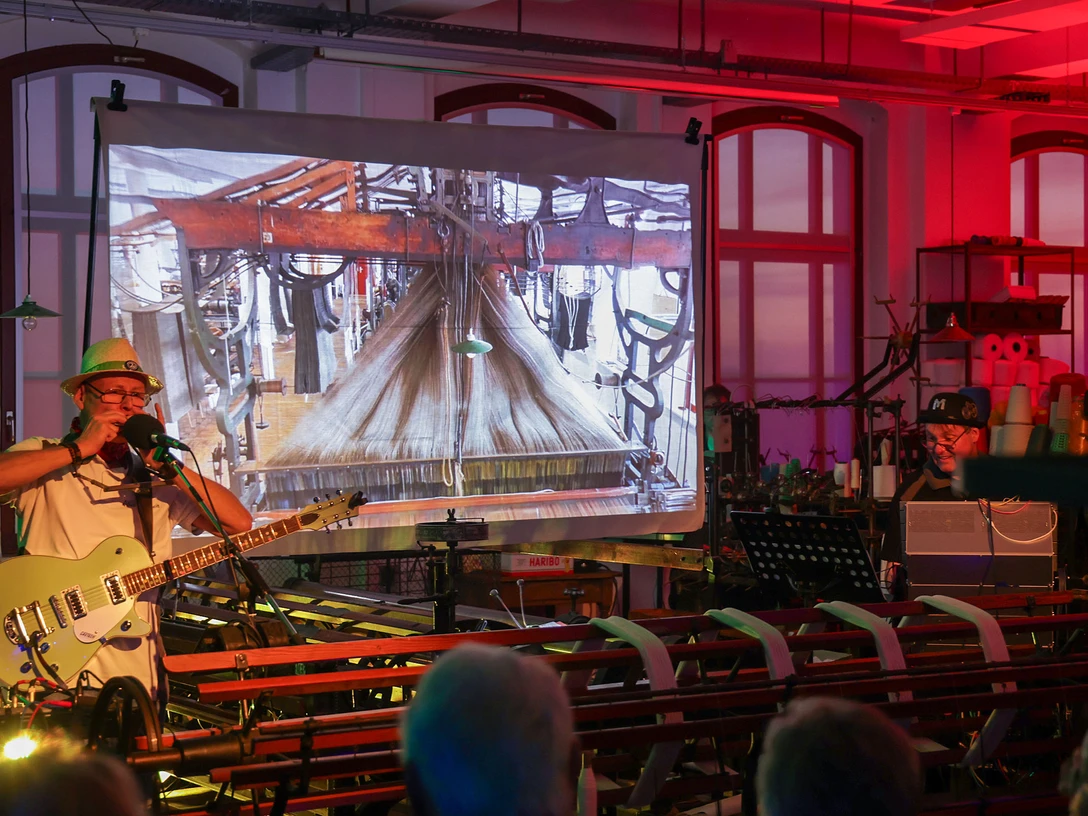 Musik und Kichtshow zwischen Strickmaschienen Musik und Kichtshow zwischen StrickmaschienenMusic and knitting show between knitting machinesHudební a pletací show mezi pletacími strojiMuzyka i pokaz robienia na drutach między maszynami dziewiarskimiMuziek- en breishow tussen breimachinesSpettacolo di musica e lavoro a maglia tra macchine per maglieria