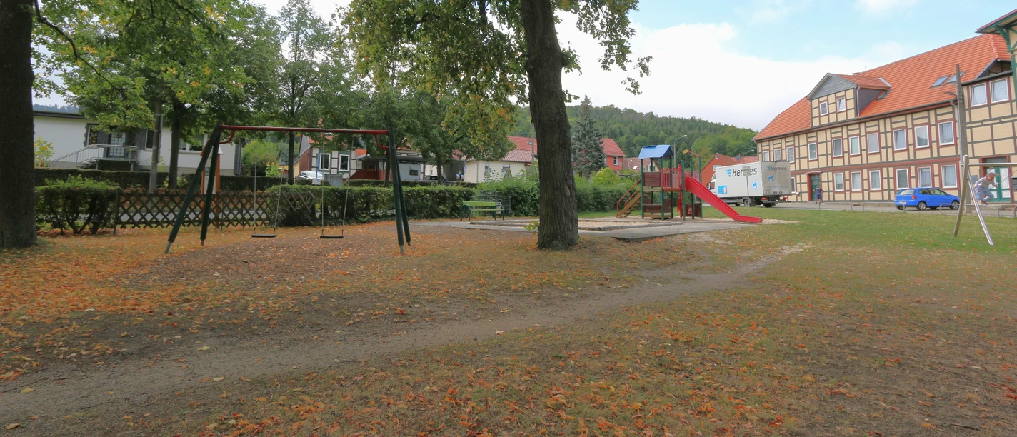 Drägetal Hasserode.JPG Spielplatz im Drängetal mit Schaukeln, Rutsche, Bäumen und Fachwerkhaus.
