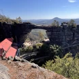Aussicht Prebischtor Im Vordergrund ein Dach der Gaststätte im Hintergrund aus Sandsteinfelsen ein großes Felsentor