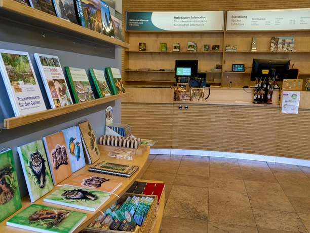 Binnenzicht van het National Park Visitor Centre met boeken en souvenirs op planken, receptie op de achtergrond.