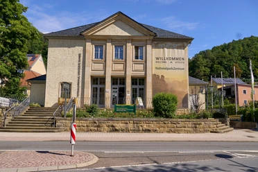 Nationalparkzentrum Klassisches Gebäude mit Säulen und "Willkommen im Nationalpark-Zentrum" Banner, vor blauem Himmel.