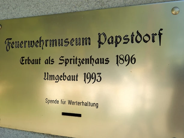 Gouden gedenkplaat met opschrift "Brandweermuseum Papstdorf, gebouwd als brandweerkazerne in 1896, herbouwd in 1993, donatie voor conservering met gleuf.