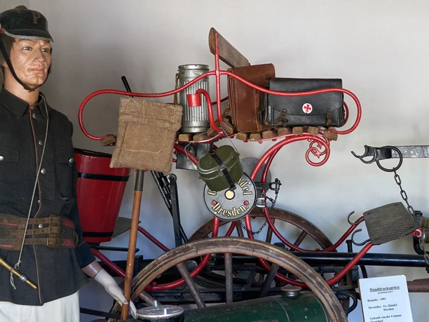 Feuerwehrmuseum Papstdorf Mann als Puppe in Uniform neben historischem Feuerwehrfahrrad mit Ausrüstung in Museum.