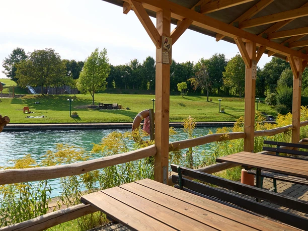 Holzterrasse mit Blick auf das Bad mit Bäumen.