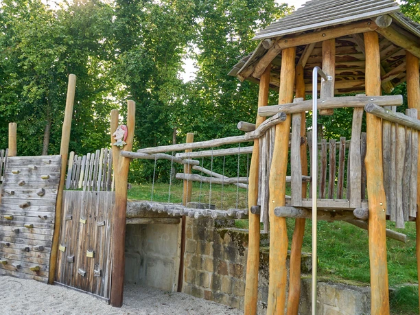 Houten speeltuin met klimrek en glijbaan.