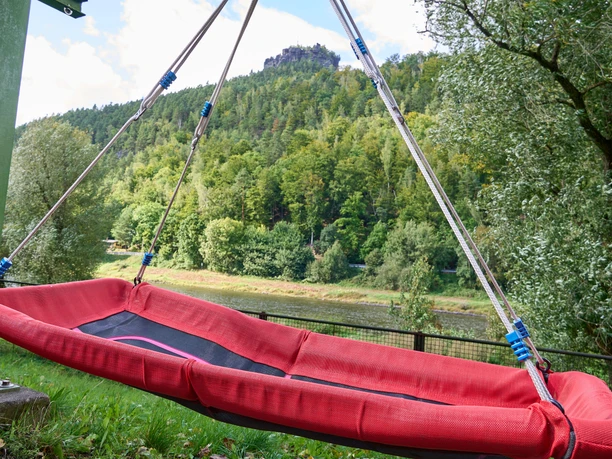 Rode hangmat met uitzicht op beboste heuvel met Lilienstein en Elbe.