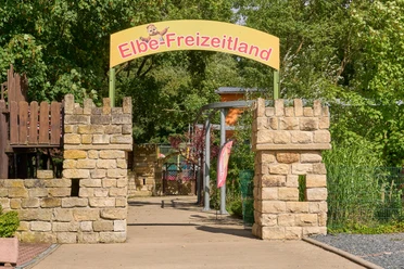 Toegangshek tot Elbe-Freizeitland met geel bord en stenen pilaren.