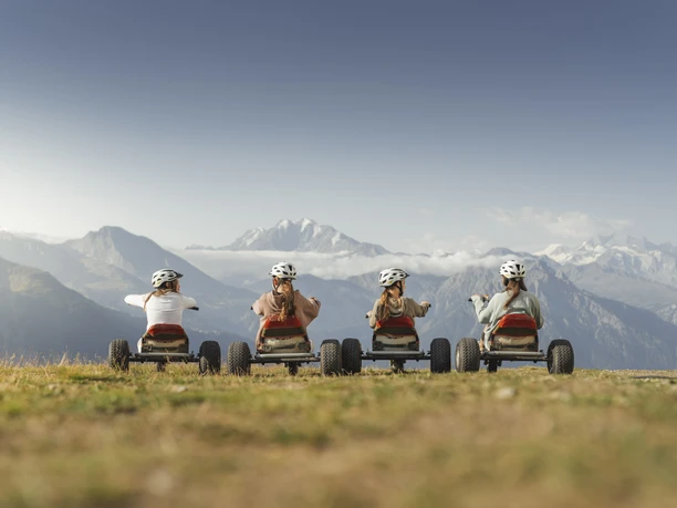 Bergab mit Blick auf die Alpen Adventure Pass Aletsch Arena mit vier Fahrerinnen auf Mountaincarts und grandiosem Blick auf die Walliser Berggipfel