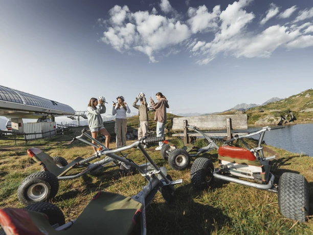 Helmet on and off you go! Adventure Pass Aletsch Arena with four friends preparing for their mountain cart descent and putting on helmets