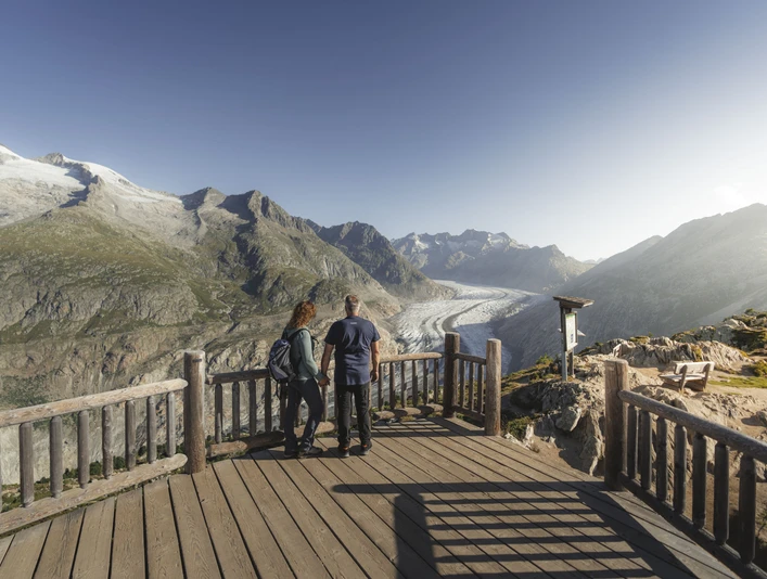 Panorama of the Aletsch Glacier Aletsch Entdeckerpass mit Paar am Aussichtspunkt Moosfluh mit Blick auf den Grossen AletschgletscherAletsch Discovery Pass with couple at the Moosfluh viewpoint with a view of the Great Aletsch GlacierPasseport découverte d'Aletsch avec couple au point de vue de Moosfluh avec vue sur le grand glacier d'Aletsch