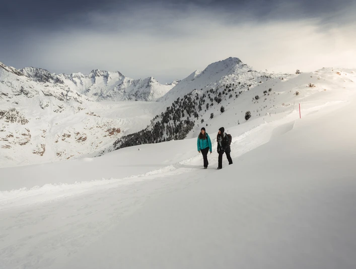 Randonnée hivernale avec vue Aletsch Entdeckerpass mit zwei Frauen beim Winterwandern in der verschneiten Landschaft mit Blick auf den AletschgletscherAletsch Discovery Pass with two women winter hiking in the snowy landscape with a view of the Aletsch GlacierPasseport découverte d'Aletsch avec deux femmes en randonnée hivernale dans un paysage enneigé avec vue sur le glacier d'Aletsch