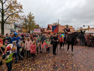 Ein Ritter reitet in historischer Kleidung, umgeben von feiernden Menschen.