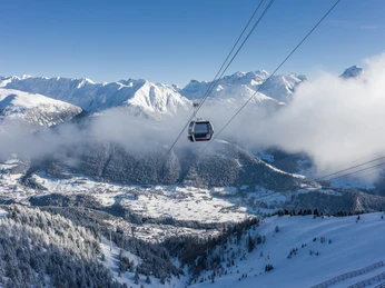 Gondola ride over wintry Fiesch Einzelfahrten Aletsch Arena mit Gondel über verschneiten Wäldern und Blick auf das Dorf Fiesch und die Walliser AlpenSingle rides in the Aletsch Arena with gondola over snow-covered forests and views of the village of Fiesch and the Valais AlpsCourses individuelles Aletsch Arena avec la télécabine au-dessus des forêts enneigées et vue sur le village de Fiesch et les Alpes valaisannes