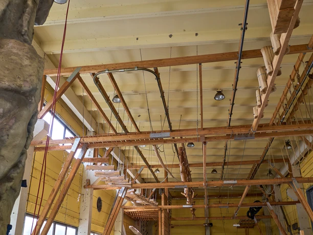 Indoor Hochseilgarten Blick auf die Deckenkonstruktion einer Kletterhalle mit Holzbalken und Kletterelementen.
