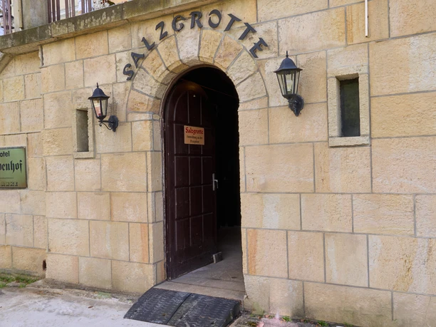 Salzgrotte Lindenhof Steinportal mit Holztür, darüber Schriftzug "Salzgrotte", zwei Wandlampen.