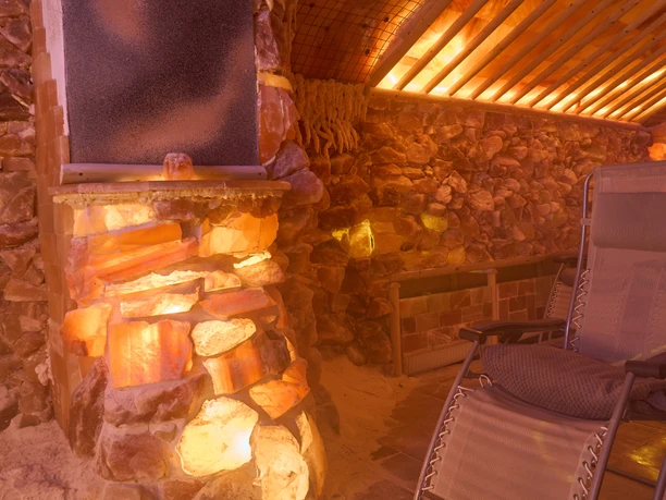 Illuminated salt stones in the salt grotto with wooden loungers and blankets.