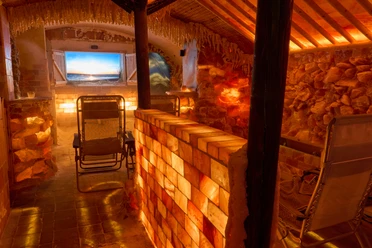 Zoutkamer met verlichte zoutstenen muren, ligstoelen en televisie.