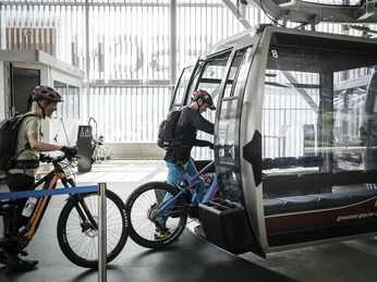 With the bike into the gondola - start in Fiesch Bike Transport Aletsch Arena mit Bikern beim Einstieg in die Gondelbahn Fiesch-Fiescheralp mit E-BikesBike Transport Aletsch Arena with bikers boarding the Fiesch-Fiescheralp gondola lift with e-bikesBike Transport Aletsch Arena avec des vététistes à l'entrée de la télécabine Fiesch-Fiescheralp avec des e-bikes