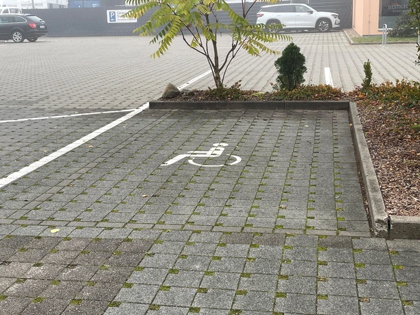 Disabled parking space Brauhaus zum Gießer Gray paved parking lot with wheelchair accessible signs