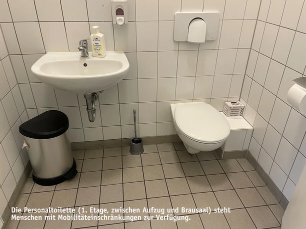 Personaltoilette.jpg Badezimmer, weiß gefliest mit Waschbecken, Mülleimer und Toilette