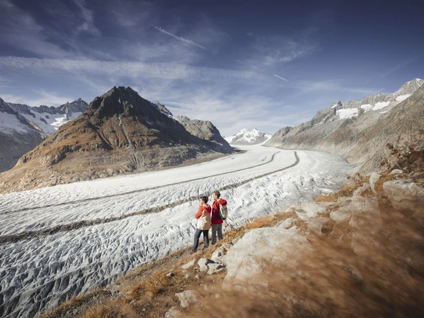 Wanderung entlang des Aletschgletschers Herbstsonne Aletsch Arena mit Wanderpaar auf Pfad entlang des Aletschgletschers im Spätherbst