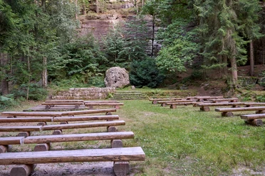 Waldbühne Leupoldishain Freiluftbühne im Wald mit hölzernen Sitzbänken und einer Felswand im Hintergrund.