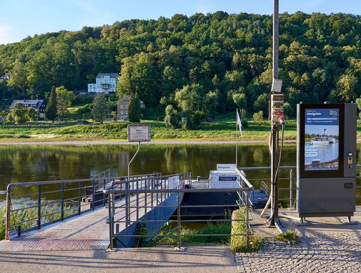 Dampfschiff-Anlegestelle Königstein Anlegestelle an der Elbe mit digitalem Information- und Ticketkiosk, Bäumen im Hintergrund.