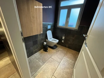 Disabled WC.jpg Toilettenraum mit Wickeltisch an der Wand, WC Becken und großzügigem Fenster Toilet room with changing table on the wall, toilet bowl and large windowToaleta s přebalovacím pultem na stěně, toaletní mísou a velkým oknem.Toiletruimte met luiertafel aan de muur, toiletpot en groot raamToaleta z przewijakiem na ścianie, muszlą klozetową i dużym oknemSala da bagno con fasciatoio a parete, vaso e grande finestra