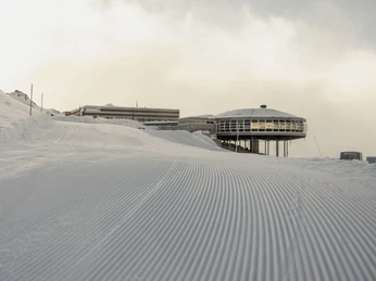 First tracks in the snow on the Bettmerhorn First Track Bettmerhorn mit frisch präparierter Skipiste bei Morgendämmerung und Blick auf die BergstationFirst Track Bettmerhorn with freshly groomed ski slope at dawn and view of the mountain stationFirst Track Bettmerhorn avec piste de ski fraîchement préparée à l'aube et vue sur la station supérieure