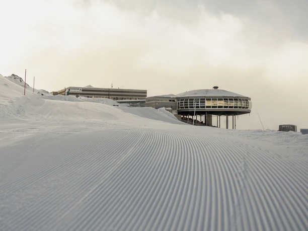 First tracks in the snow on the Bettmerhorn First Track Bettmerhorn with freshly groomed ski slope at dawn and view of the mountain station