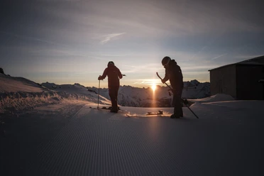 Départ à ski aux premières lueurs du jour First Track Bettmerhorn avec des skieurs au lever du soleil sur une piste de ski fraîchement préparée de l'Aletsch Arena