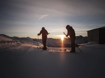 Skistart im ersten Licht des Tages First Track Bettmerhorn mit Skifahrern im Sonnenaufgang auf frisch präparierter Skipiste der Aletsch ArenaFirst Track Bettmerhorn with skiers at sunrise on a freshly groomed ski slope in the Aletsch ArenaFirst Track Bettmerhorn avec des skieurs au lever du soleil sur une piste de ski fraîchement préparée de l'Aletsch Arena