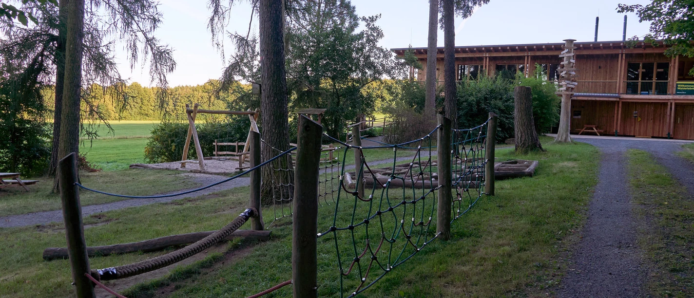 Holzhaus mit Spielplatz in einem bewaldeten Park.