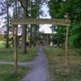 Walderlebniszentrum Holzschild "Walderlebniszentrum" über einem Weg, der in einen Park führt.Wooden sign "Forest Experience Center" above a path leading into a park.Dřevěná cedule "Forest Experience Centre" nad cestou vedoucí do parku.Drewniany znak "Forest Experience Centre" nad ścieżką prowadzącą do parku.Houten bord "Forest Experience Centre" boven een pad dat naar een park leidt.Cartello in legno "Forest Experience Centre" sopra un sentiero che conduce a un parco.